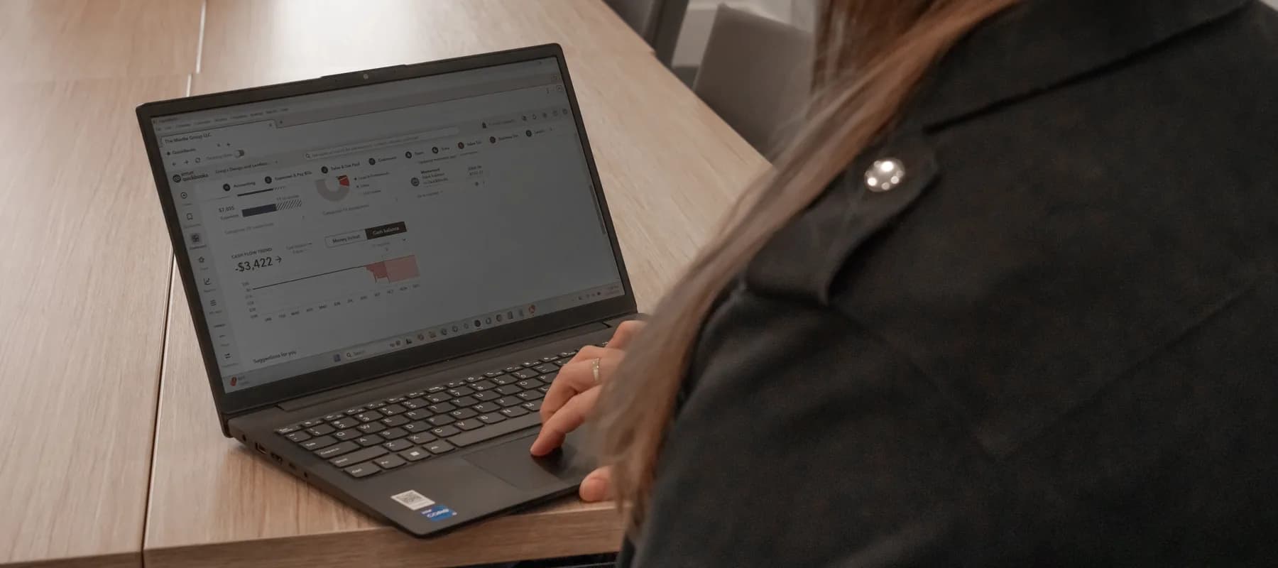 Over the shoulder of a team member reading a client’s financial dashboard on a laptop