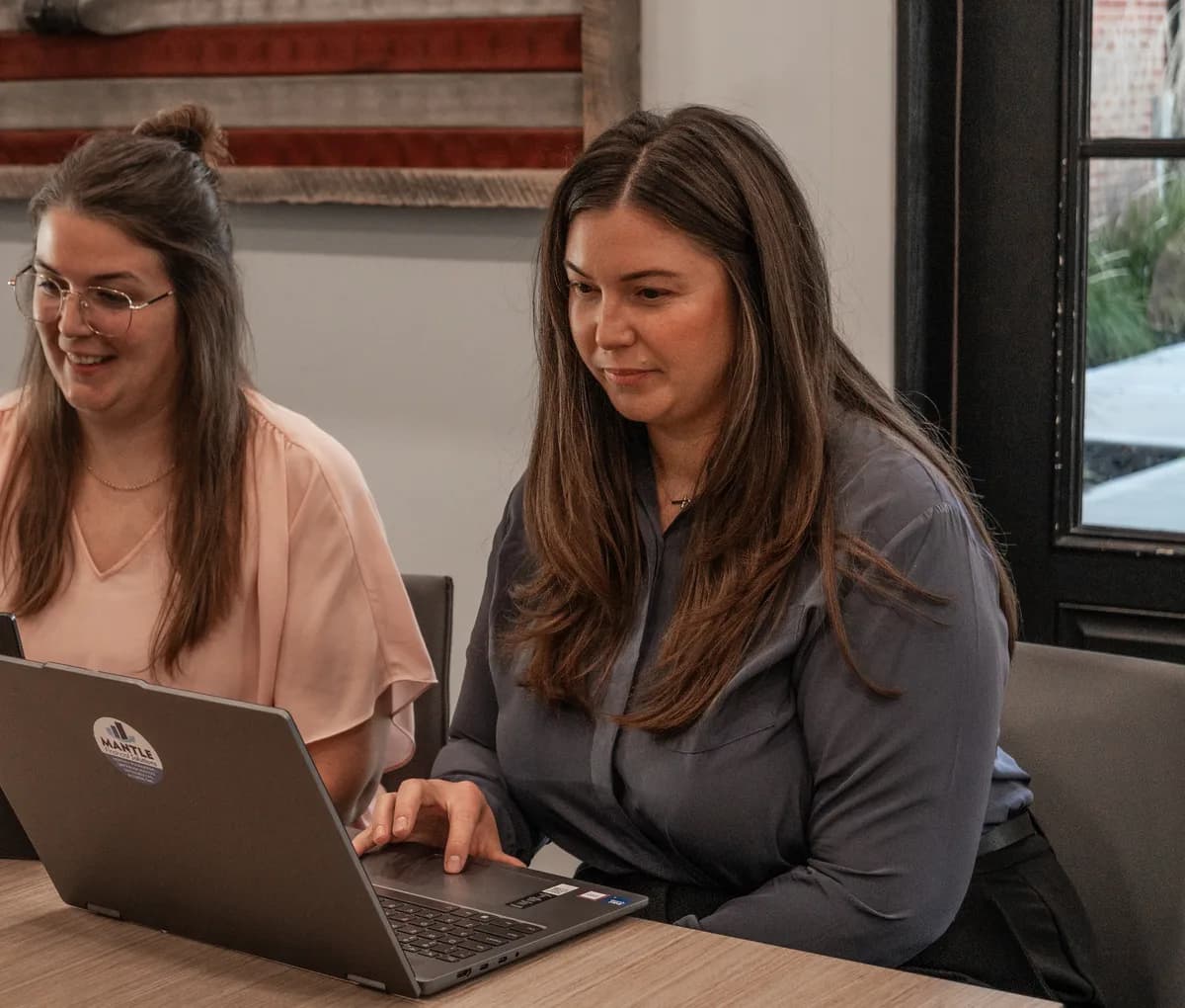 Two members of the team working at laptops in the firm’s conference room