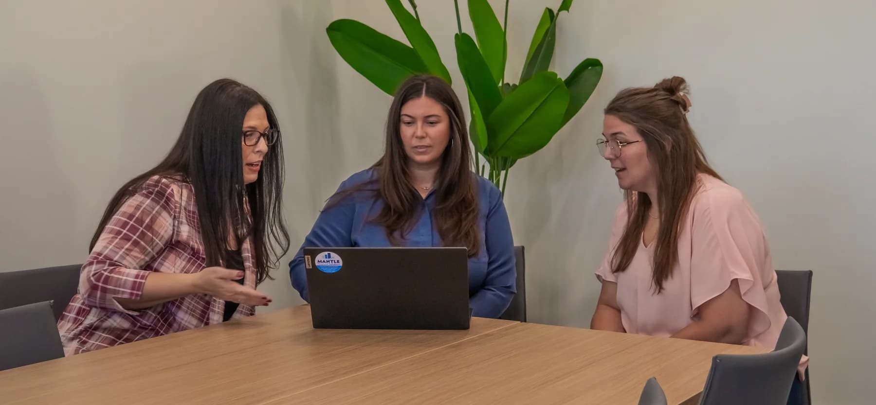Hava Laudon talking through a file on screen with two of her team at a conference table
